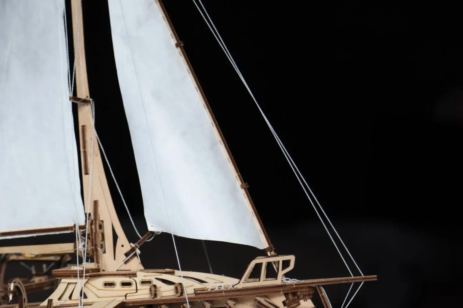 Wooden sailboat model reflected in a dark glass table